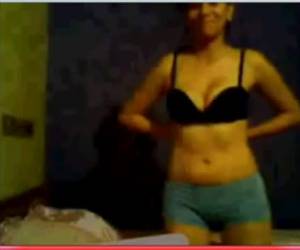 Het verlegen meisje geeft een striptease voor de webcam en laat haar blote tieten zien.
